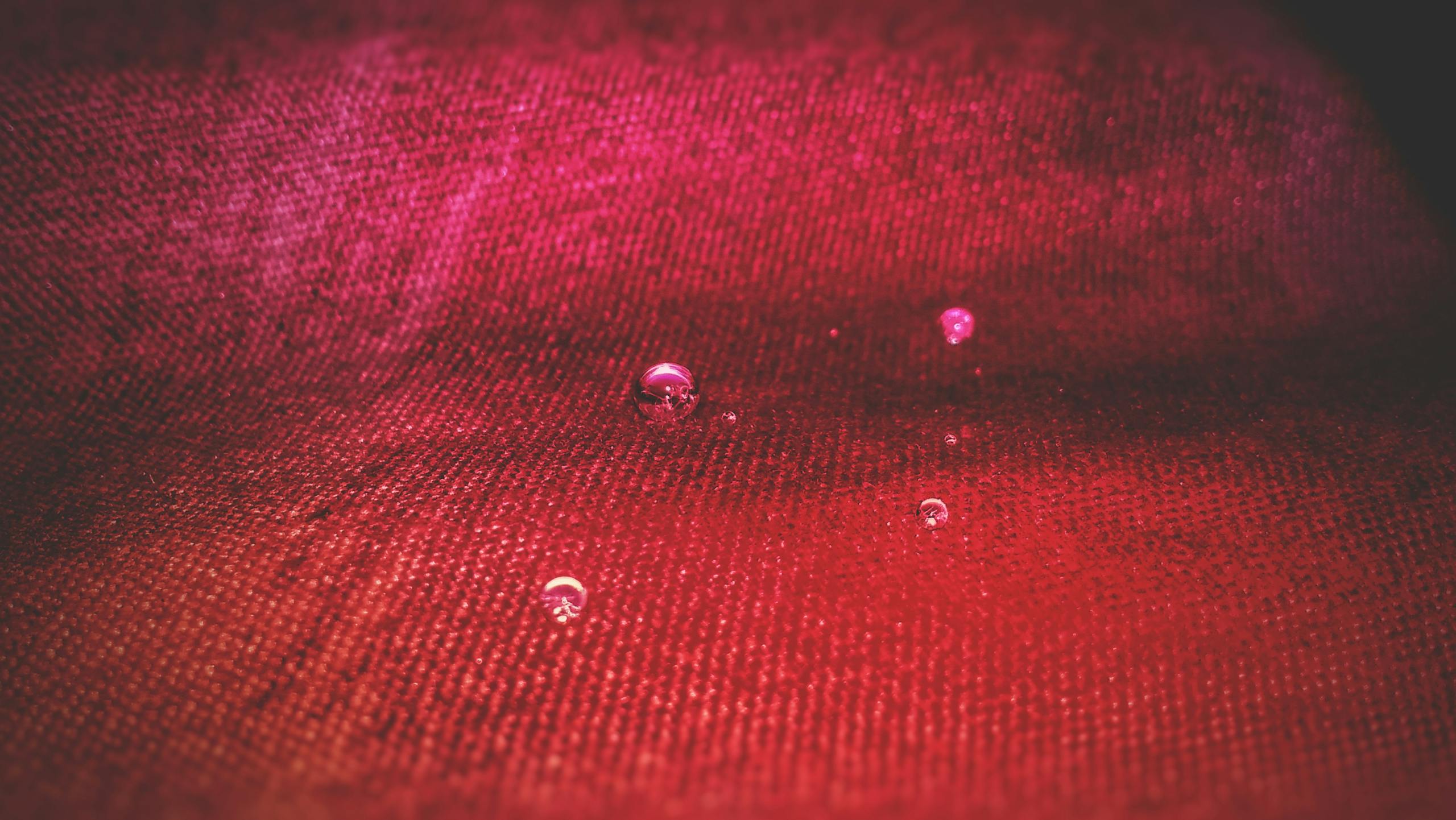 ventsMagazine Close-up view of water droplets resting on vibrant red textile surface.