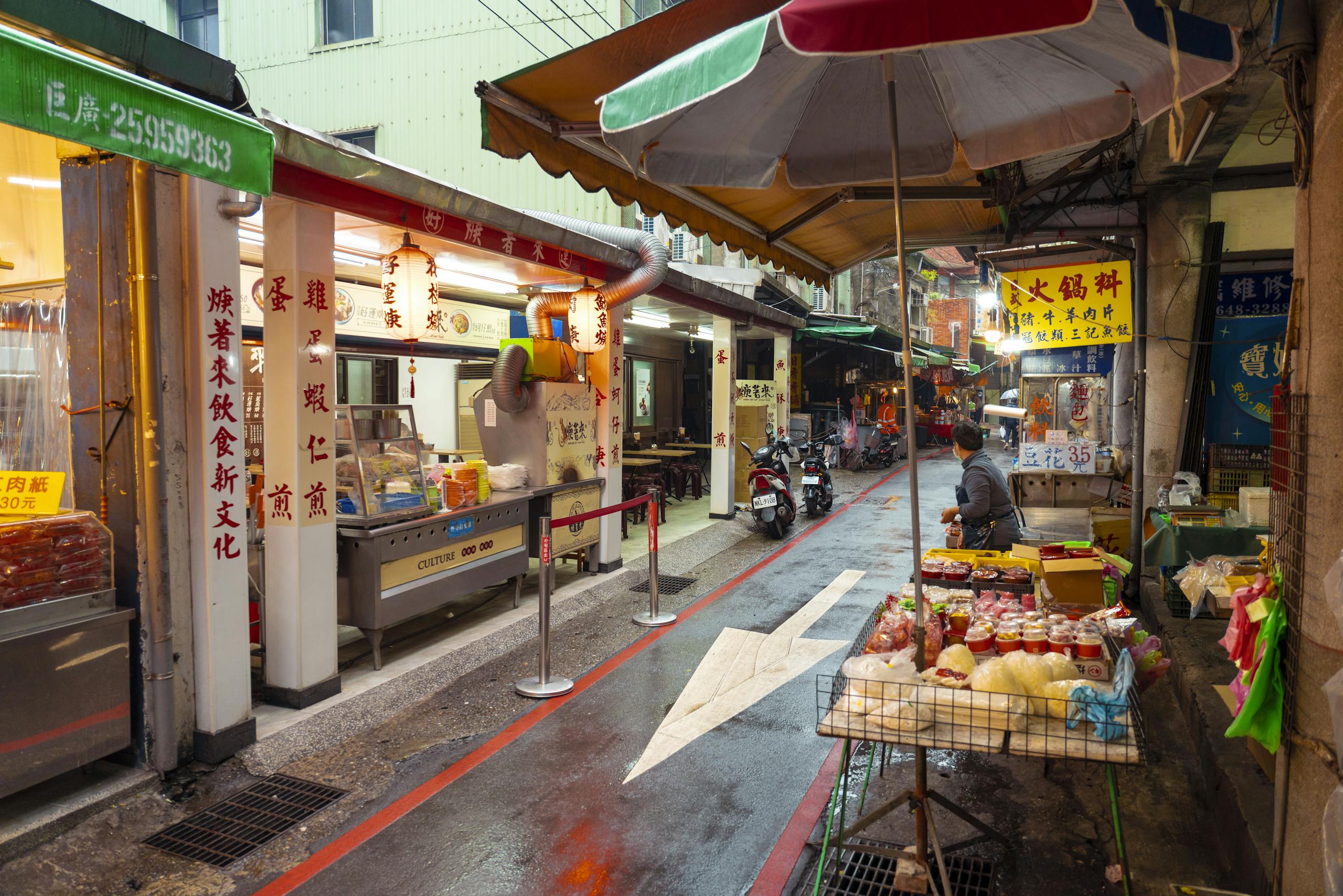 Cray0lav0mit Colorful street market with food stalls and merchandise in an Asian city.