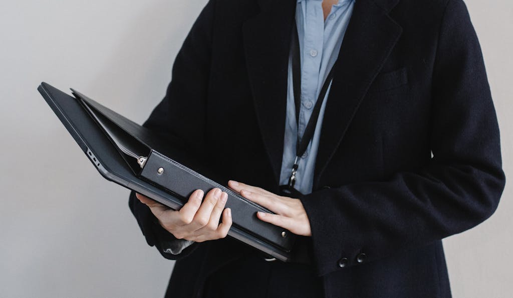 Blazertje Crop unrecognizable professional office worker in formal clothes standing against white wall with folders in hands