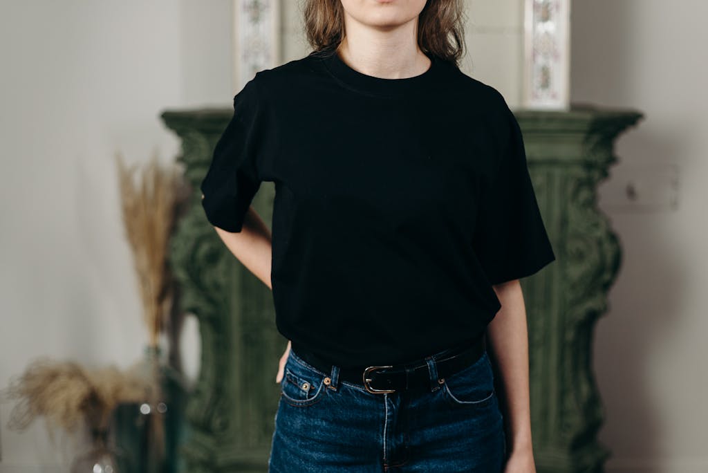 HerbCiepScam Faceless model in black t-shirt and jeans showcasing minimalist fashion style indoors.