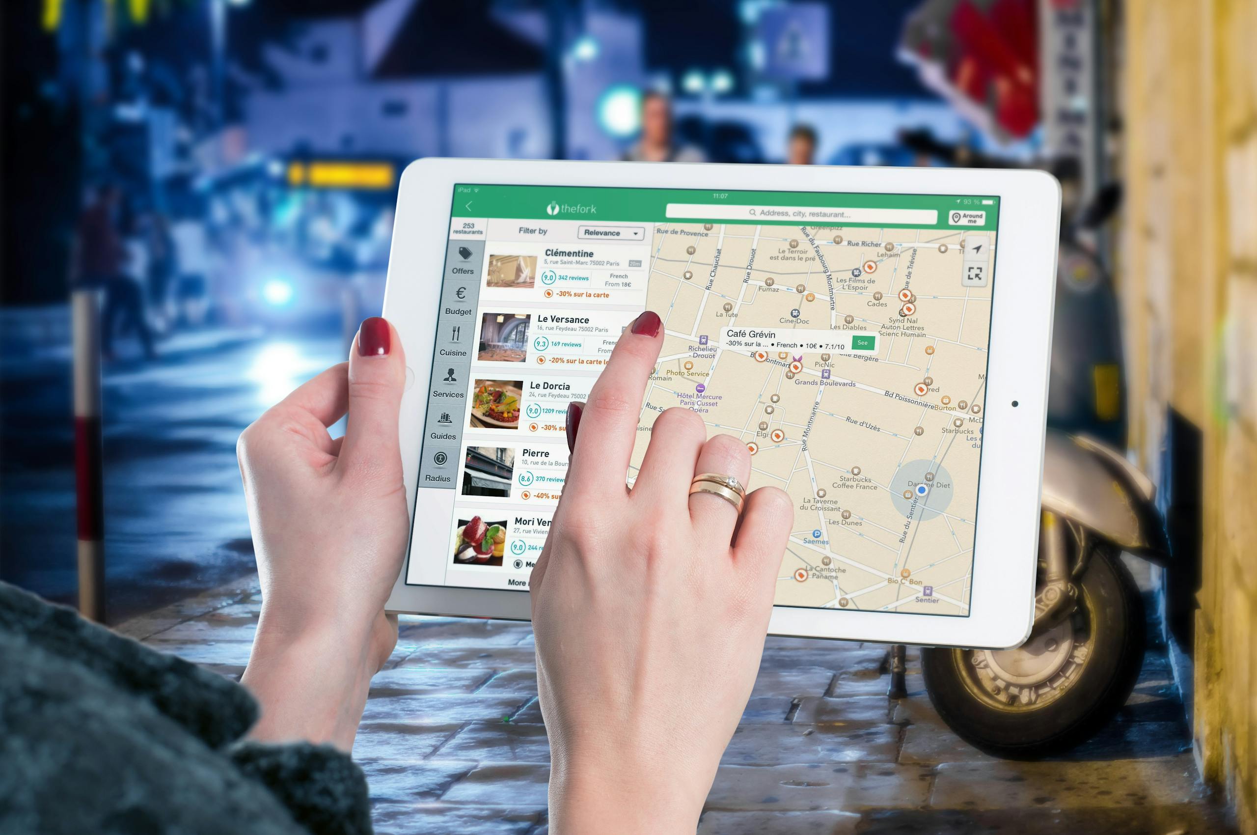 Kongotech Org Hands using a digital map on a tablet in an urban setting at night, illustrating navigation and technology.