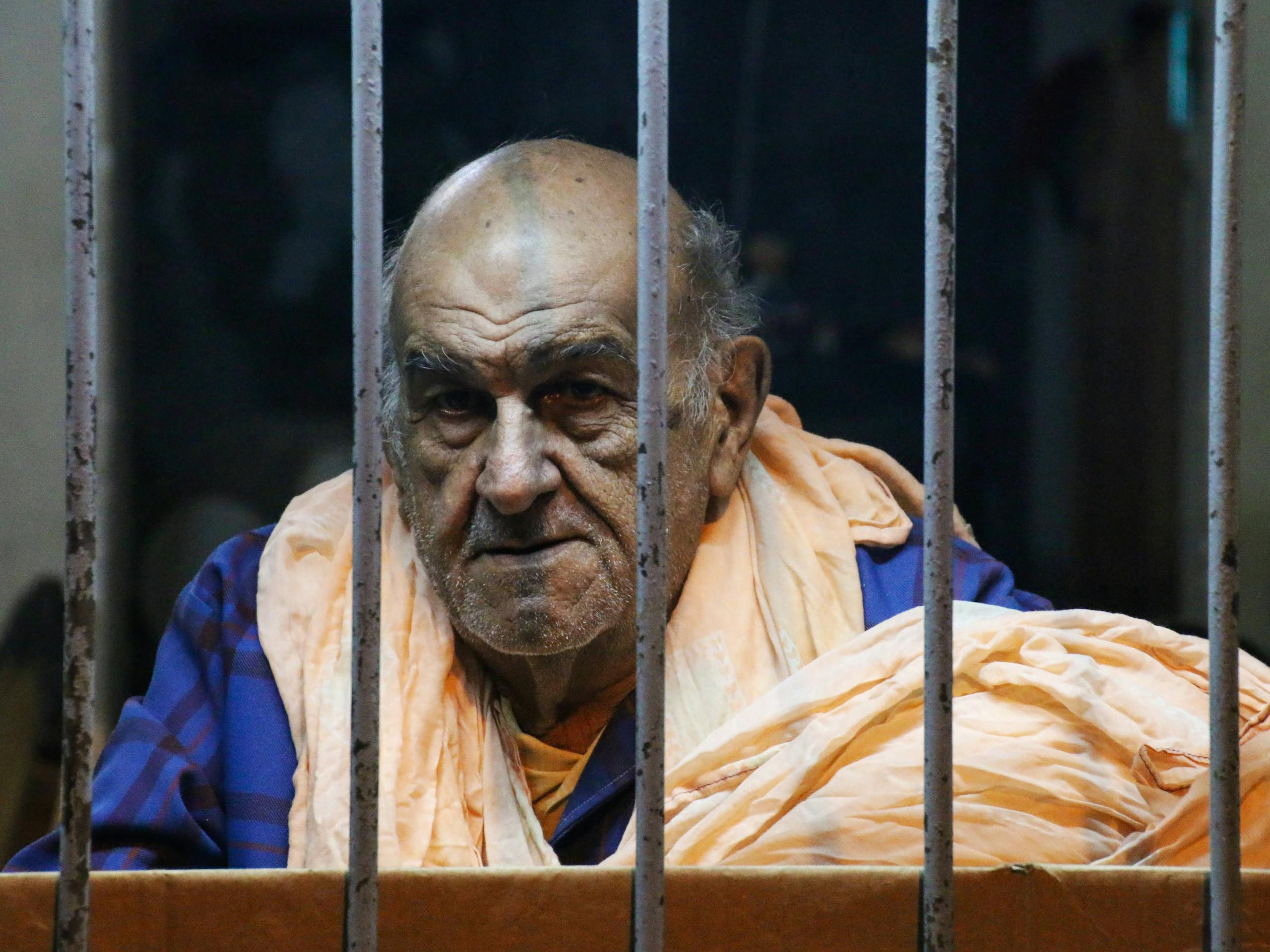 Hormita Portrait of an elderly man behind bars wearing casual clothing, conveying a thoughtful mood.