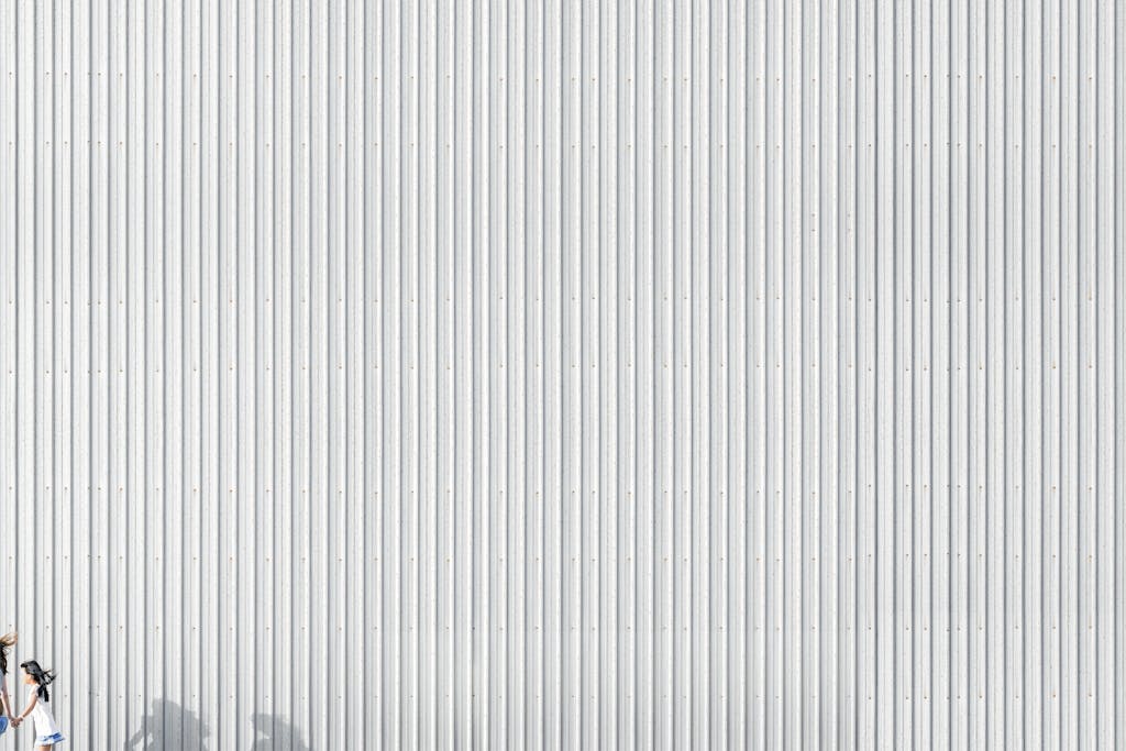 FamousParentingMomLife Silhouette of a woman running against a corrugated metallic wall, showcasing minimalist design and light play.