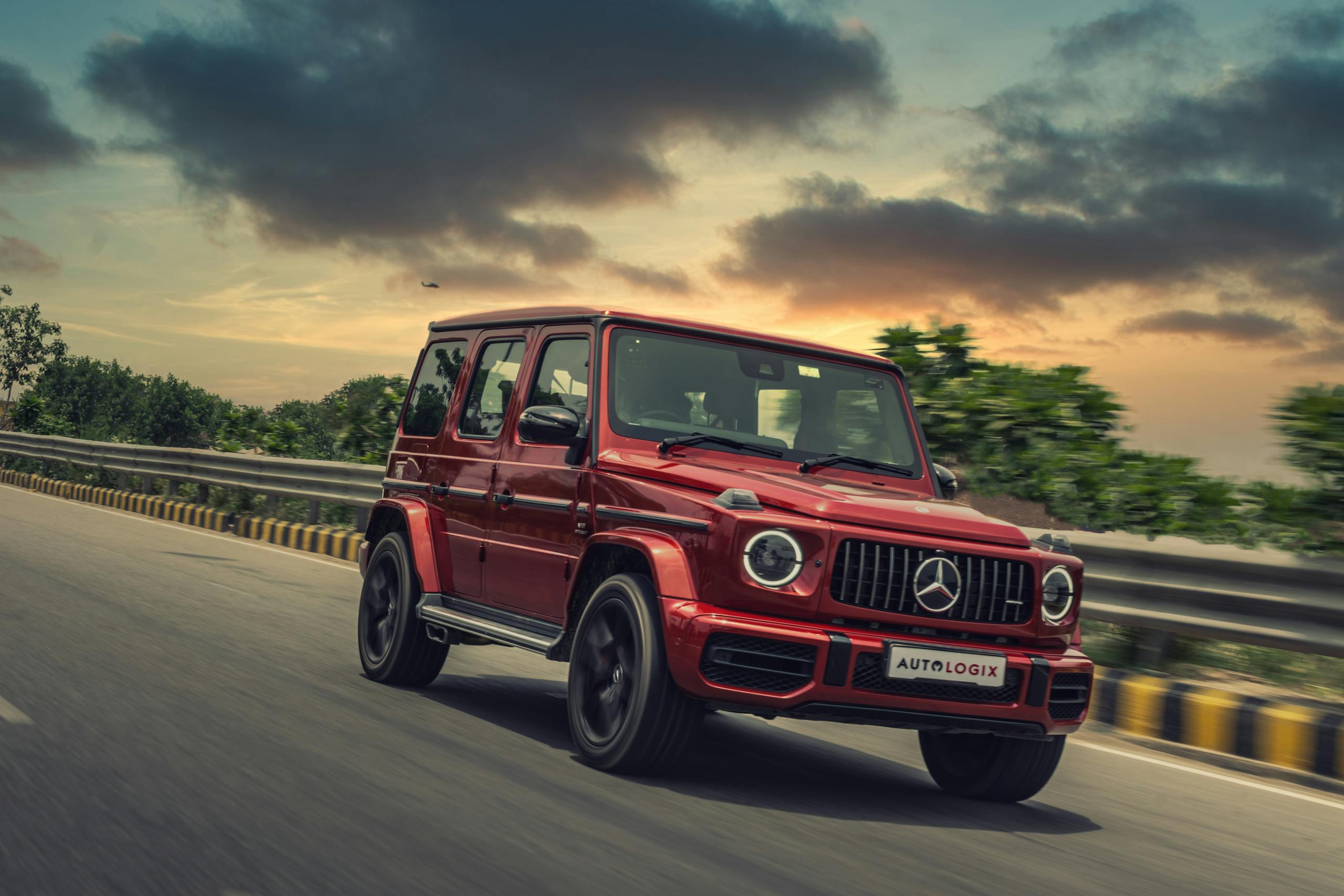 Unbanned G+ A red Mercedes SUV drives swiftly on a highway at sunset, showcasing luxury and speed.