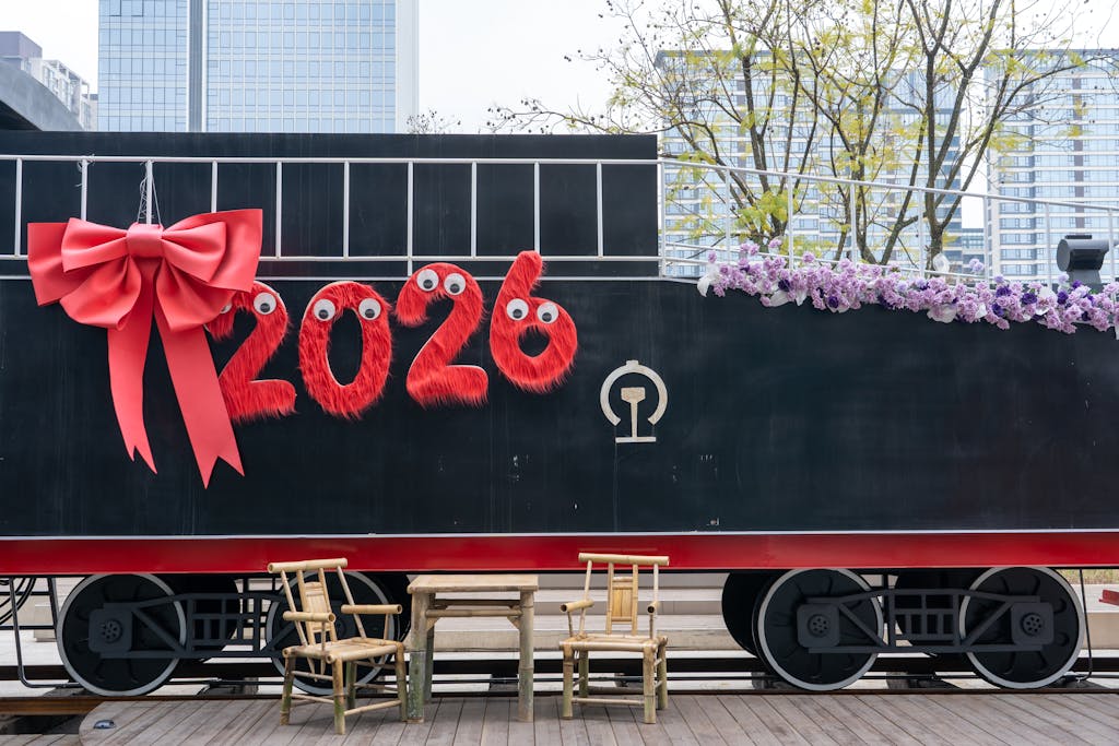 IPL League 2026  A festive train decorated with '2026' and a red bow, set in an urban environment.